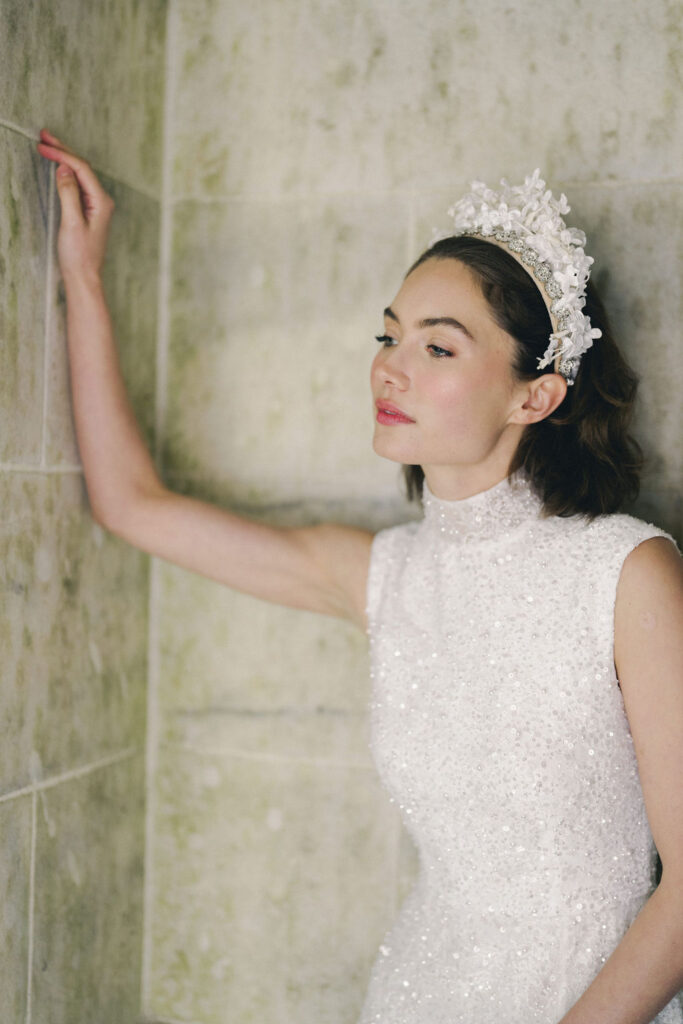 bride leaning against wall in beaded wedding dress
